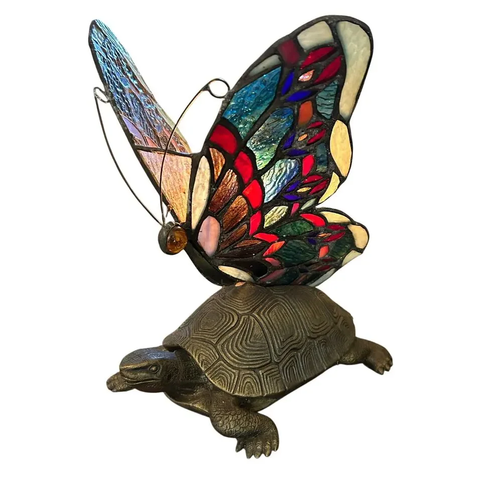 Vintage Tiffany style stained glass butterfly lamp resting on a brass turtle
